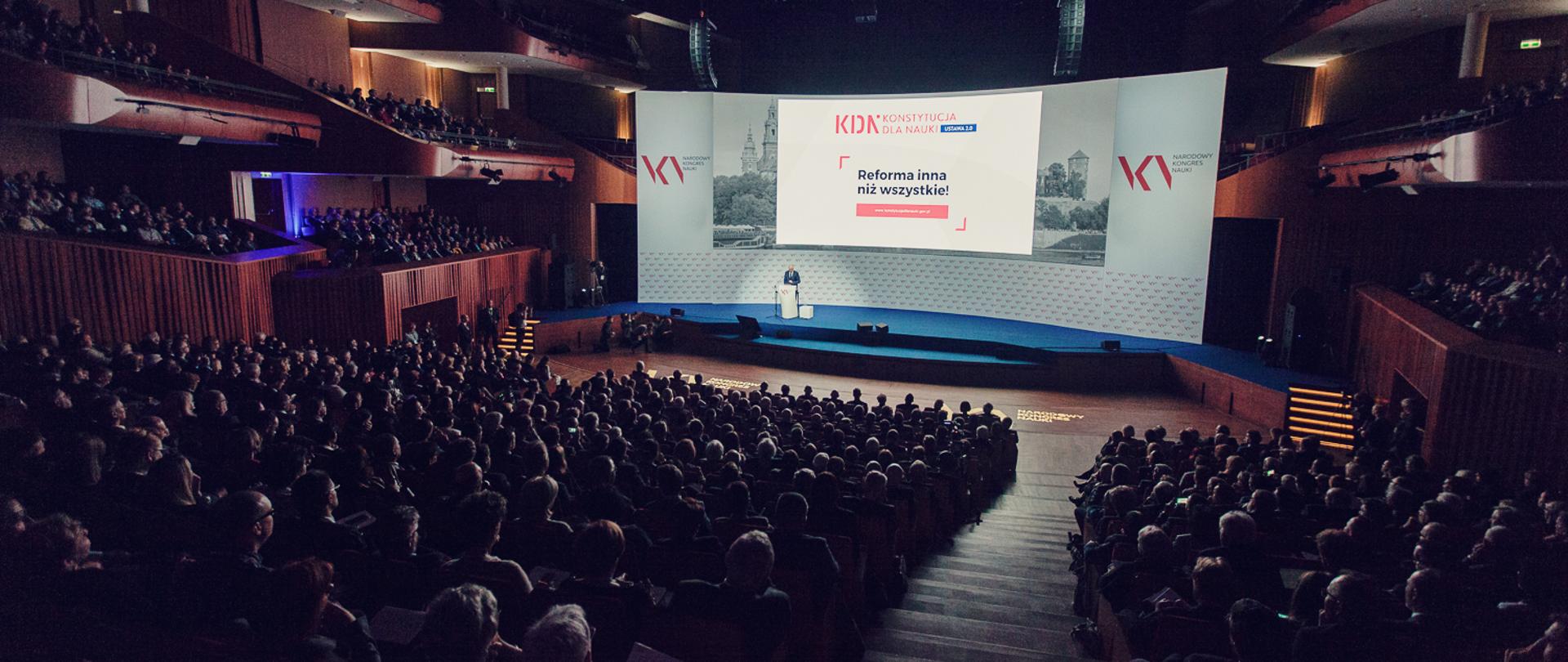 Na zdjęciu pełna widownia w centrum kongresowym, w oddali scena. Na telebimie napis "Reforma inna niż wszystkie"